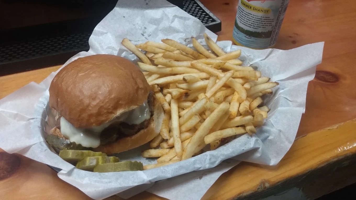 Cheeseburger on a brioche bun with seasoned fries and pickles